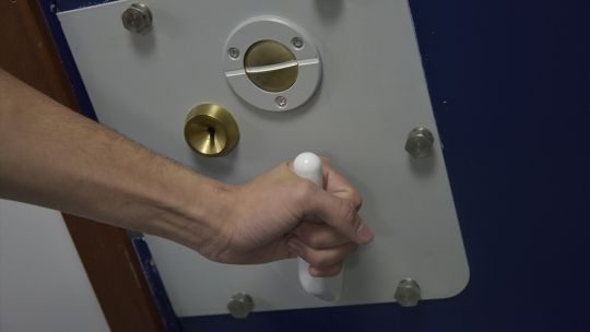A police cell door handle being turned closed
